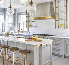 a kitchen with white cabinets and gold accents