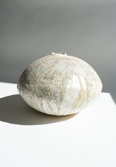 a white rock sitting on top of a white table next to a gray and white wall