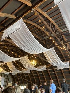 a large group of people standing in a room with white drapes hanging from the ceiling