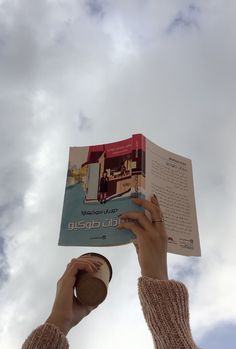 a person is holding up a book in the air with their hands on top of it