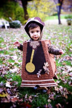 a little boy dressed up as a musical instrument in the grass with leaves on the ground