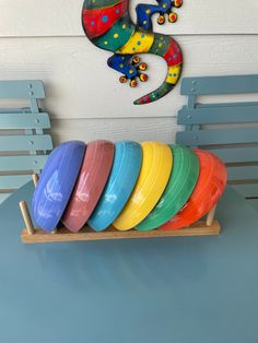 colorful plates are stacked on a wooden tray in front of a gecko wall decoration