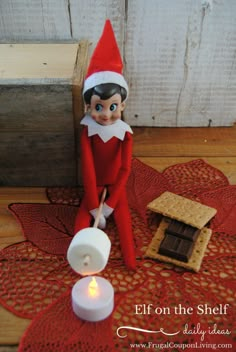 an elf is sitting on the table next to a lit candle and some crackers