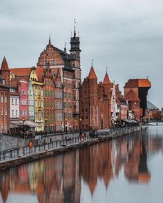 the buildings are reflected in the water on the side of the street near the river