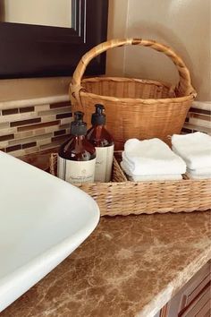 a bathroom counter with soaps and lotion bottles in front of a basket on the sink