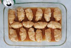 a glass dish filled with dumplings covered in gravy next to a can of soda