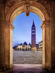 an archway leading to a building with a clock tower in the background