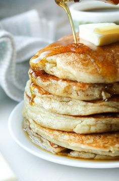 a stack of pancakes with butter and syrup being drizzled on top