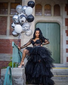 a woman in a black dress sitting on steps with balloons