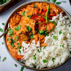 a bowl filled with rice and meat covered in sauce