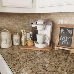 a coffee maker sitting on top of a kitchen counter next to a chalkboard sign