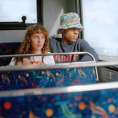 a man and woman sitting on a bus looking out the window at something in the distance