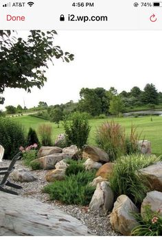 a lawn chair sitting on top of a pile of rocks next to a lush green field