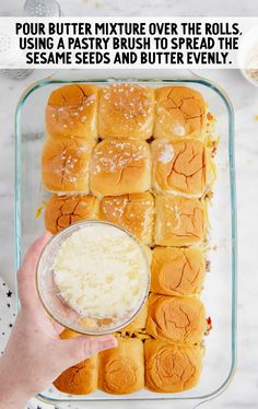 a person holding a bowl with some bread rolls in it and the text, four butter mixture over the rolls using a pastry to spread the sesame seeds and butter evenly