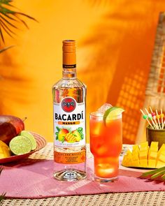 a bottle of bacardi next to a glass and plate with fruit