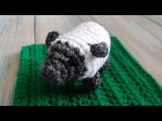 a small crocheted sheep sitting on top of a green rug