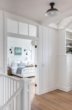 an open door leading to a bedroom with white walls and wood flooring on the other side