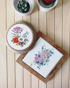 two bowls with flowers on them are next to an empty plate and some small plants