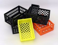 four different colored plastic baskets sitting next to each other on a white surface with no one in it