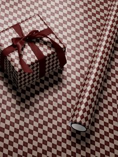 a present wrapped in brown and white checkered paper with a red bow on it