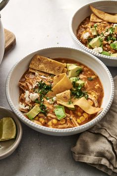 two bowls of mexican soup with tortilla chips and avocado on the side