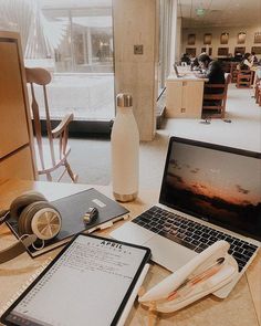 an open laptop computer sitting on top of a wooden table next to a phone and other items