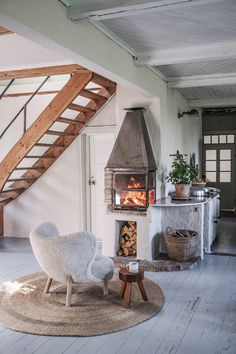 a living room with a fire place in the center and stairs leading up to it