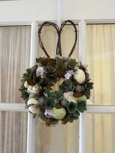 a wreath hanging from the side of a window with succulents and flowers