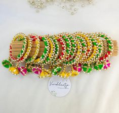 a bunch of colorful bracelets sitting on top of a white table next to a necklace