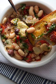 a white bowl filled with beans and vegetables on top of a blue and white napkin