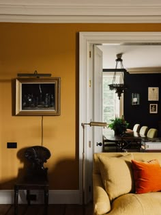 a living room filled with furniture and a painting on the wall next to a doorway