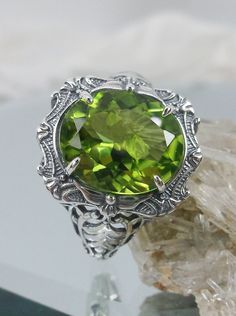 "Natural Green Peridot Ring Description Beauty Design#229 MADE To ORDER This is a brand new stunning Art Nouveau/Victorian reproduction sterling silver filigree ring. The oval-cut high-quality natural peridot is 12mm by 10mm (just shy of 3/8\" inch) in dimension... The ring is 5/8th of an inch (16.5mm) NS (long) on the finger. The ring and gem sit 7mm off the finger. The inside of the band is marked 925 for sterling. Notice the beautiful filigree swirl like the craftsmanship of the silver settin Oval Peridot Jewelry With Accent Stones, Handmade Elegant Peridot Rings, Elegant Handmade Peridot Rings, Green Oval Filigree Ring With Gemstone, Handmade Oval Peridot Rings, Green Oval Ring With Intricate Design, Oval Peridot Heirloom Jewelry, Unique Oval Filigree Ring With Gemstone, Heirloom Peridot Oval Jewelry