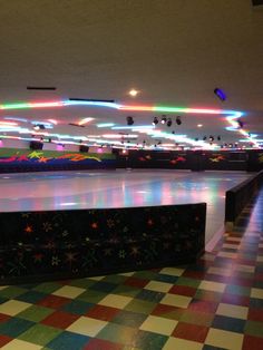 an empty skating rink with lights on the ceiling and checkered flooring around it