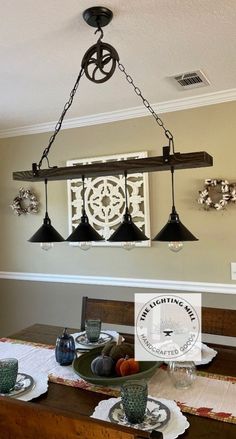 a dining room table with four lights hanging from the ceiling and plates on the table