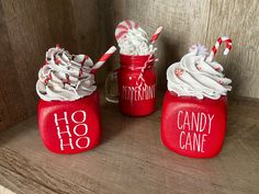 three red jars with white frosting and candy canes in them sitting on a table