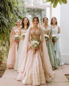 a group of women standing next to each other wearing dresses and holding bouquets in their hands