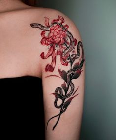 a woman's arm with red flowers and snakes tattooed on the back of her shoulder