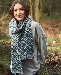 a woman standing in the woods wearing a green and white knitted cowl scarf