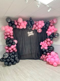 the balloon arch is decorated with black and pink balloons