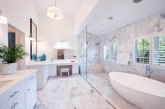 a large white bathroom with marble floors and walls, along with a freestanding tub