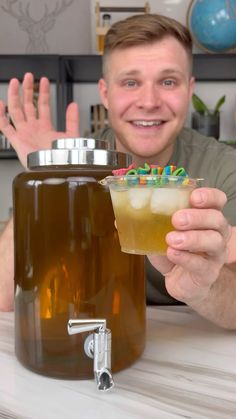 a man sitting at a table with a drink in front of him and his hands up