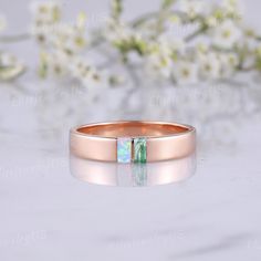 a rose gold wedding band with an opal stone in the center and a green stripe