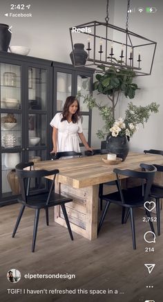 a woman standing in front of a wooden table