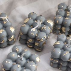 several small gray and gold candies sitting on top of a white tablecloth covered surface