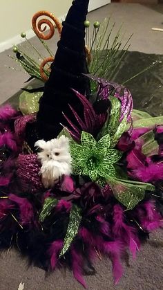 a black hat with purple feathers and an owl on it's head sitting on the floor