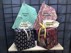 three gift bags with names on them sitting on a shelf in front of a wall