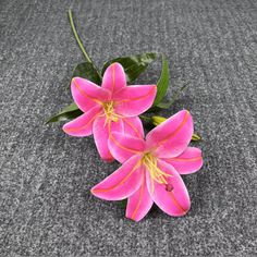 three pink flowers sitting on top of a gray carpet