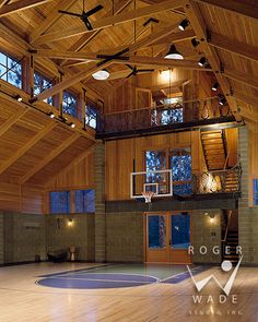 an indoor basketball court with wooden walls and ceilinging is lit by recessed lights