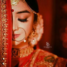 a woman wearing a red and gold bridal outfit, with her eyes closed to the side