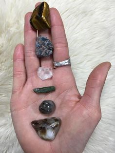 a person's hand holding various rocks and stones